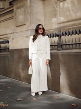 A lady wears a white jacket and white pants.
